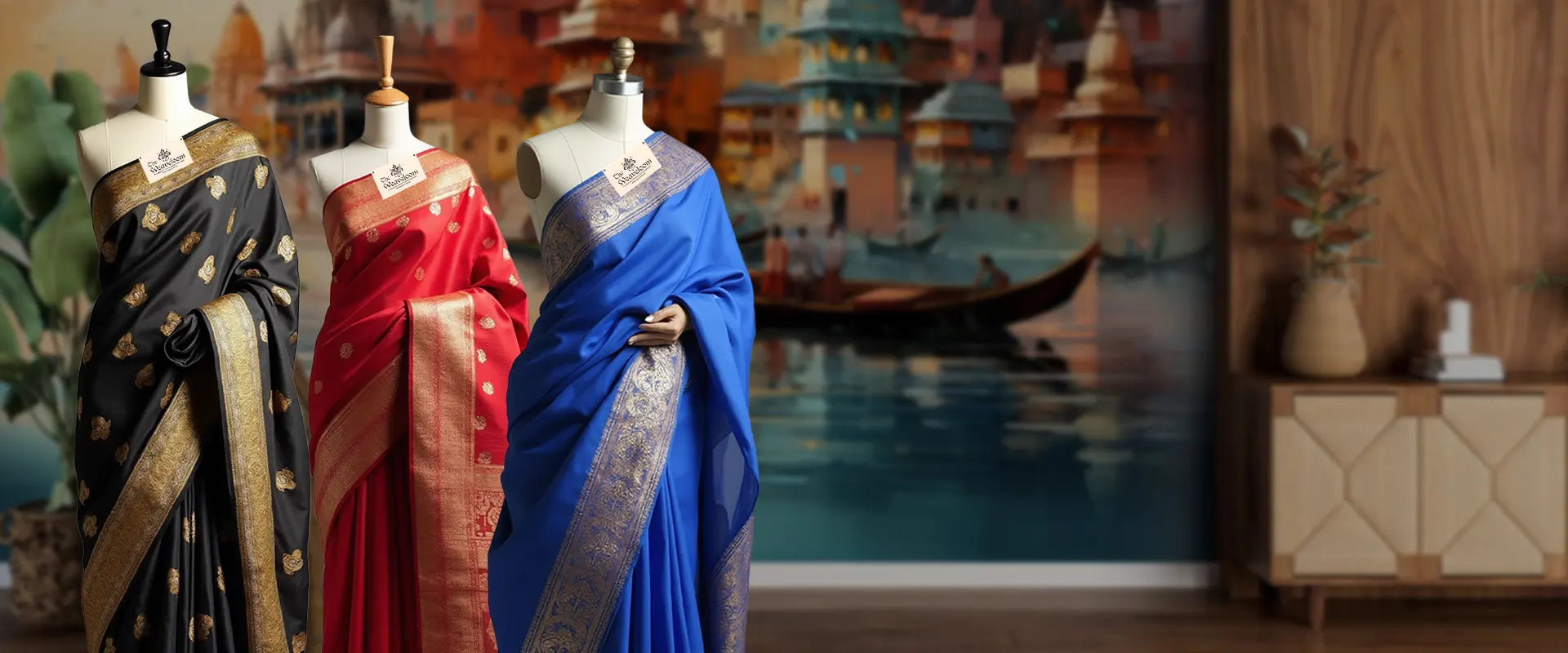 Three mannequins wearing sarees in a room with a decorative wall mural.
